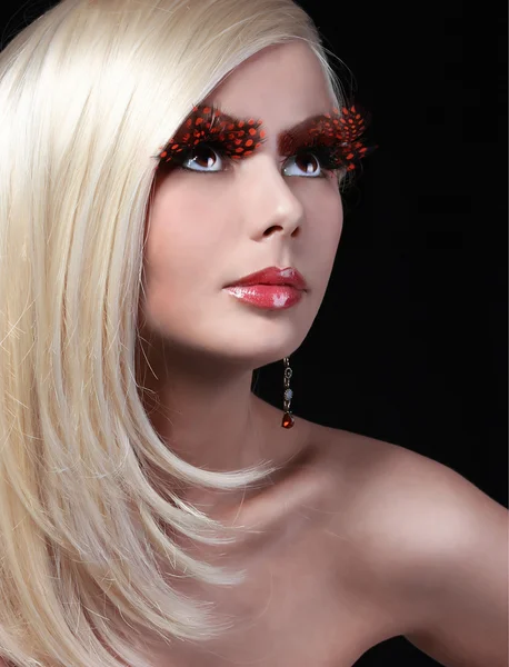 Modèle de mode blonde avec de longs cils orange. Maquillage professionnel et coiffure. Portrait de belle jeune femme, sur noir — Photo