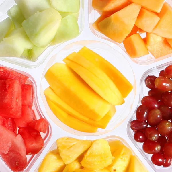 Piezas frescas de frutas en un recipiente de plástico. Vida sana. Diferentes tipos de frutas en rodajas: mango, sandía, melón, uvas, piña . —  Fotos de Stock