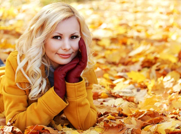 Blond meisje in herfst park met esdoorn bladeren. mooie mode — Stockfoto