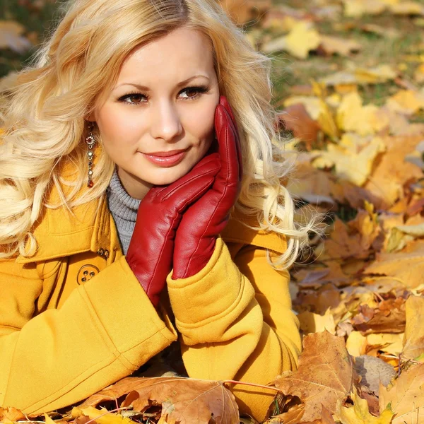 Blondes Mädchen im Herbstpark mit Ahornblättern. Mode schön — Stockfoto