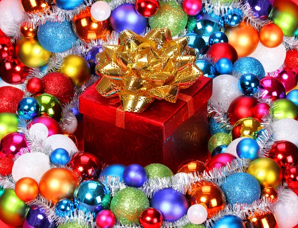 Prezent na Boże Narodzenie z złoto łuk i kolorowe kulki. Boże Narodzenie wystrój — Zdjęcie stockowe