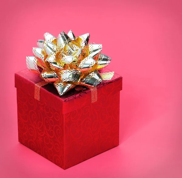 Jul presentförpackning med guld band rosett, över röd bakgrund — Stockfoto