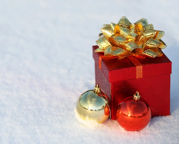 Christmas Gift Box with Shiny Balls on Snow. Outside. Winter Sun