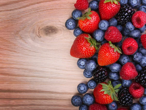 Bayas sobre fondo de madera. Fresas, arándanos, frambuesas y moras . — Foto de Stock