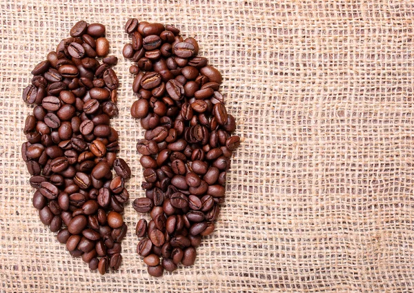 Granos de café. Colocado en forma de frijol sobre fondo de arpillera — Foto de Stock