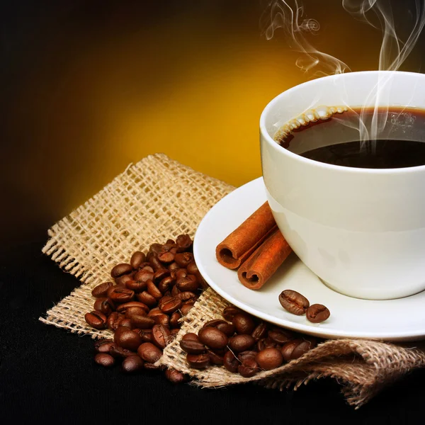 Tazza di caffè con piattino e chicchi di caffè su tela su nero — Foto Stock
