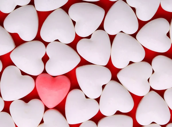 Corazón rosado entre un montón de corazones blancos. Corazones de caramelo — Foto de Stock