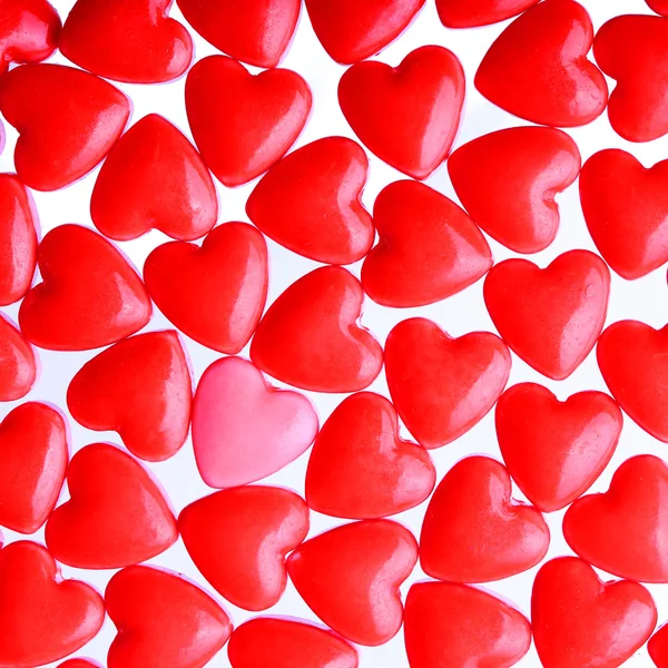 Corazón rosado entre un montón de corazones rojos. Candy Hearts fondo —  Fotos de Stock