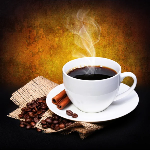 Tasse à café avec soucoupe et grains de café sur toile de jute sur fond sombre — Photo