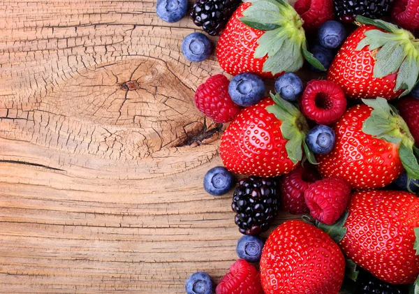 Bobule na dřevěné pozadí. jahody, borůvky — Stock fotografie