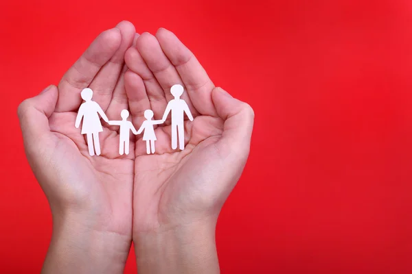 Familia de papel en manos sobre fondo rojo. Familia y niños —  Fotos de Stock