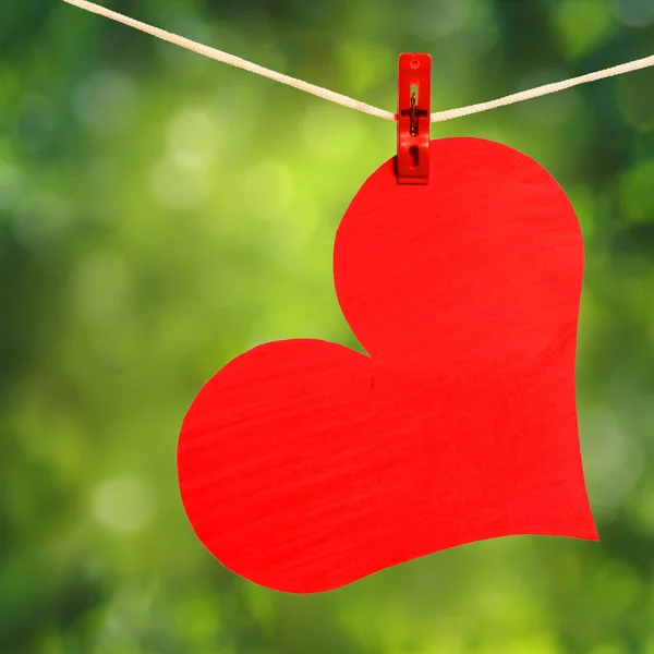 Cuore rosso con molletta appesa alla clothesline sulla natura — Foto Stock