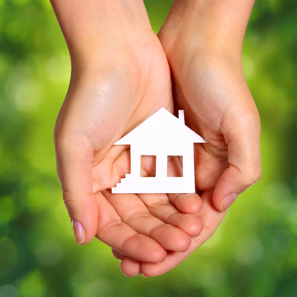 Papier huis in vrouwelijke handen over natuur groene zonnige achtergrond. — Stockfoto