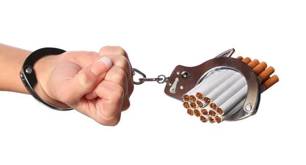 Сигареты и наручники на женской руке изолированы на белом — стоковое фото