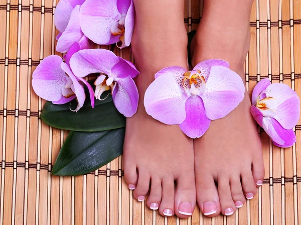 Pedicure with pink orchid flowers on bamboo mat. Beautiful — Stock Photo, Image
