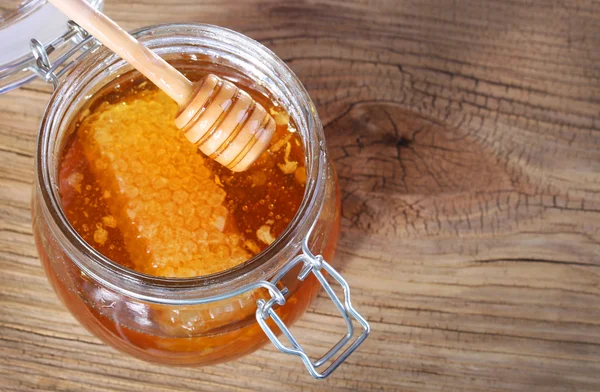 Tarro de miel con panal y cazo sobre fondo de madera — Foto de Stock