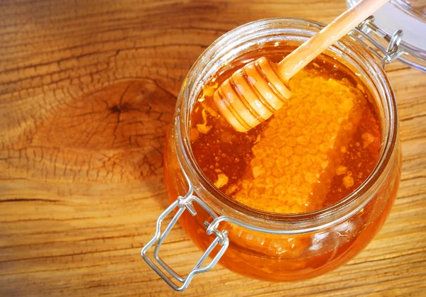 Tarro de miel con panal y cazo sobre fondo de madera — Foto de Stock