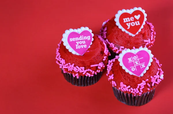 Cupcake al cioccolato con cuori rossi, su sfondo rosso . — Foto Stock