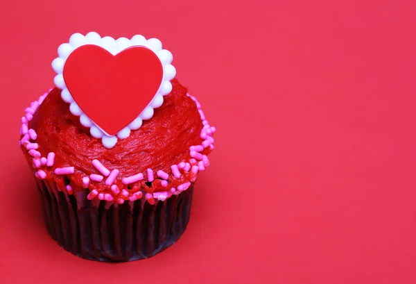 Schokoladen-Cupcake mit rotem Herz auf der Oberseite, über rotem Hintergrund — Stockfoto