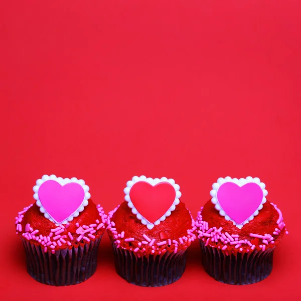 Chocolade cupcakes met Valentijn harten op de toppen, over rood — Stockfoto