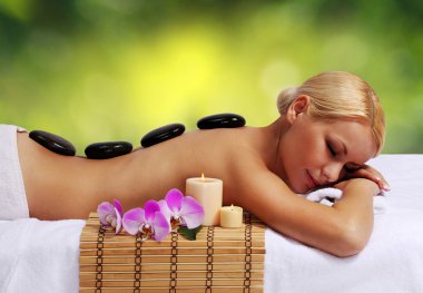 Spa taş masajı. güzel sarışın sıcak masaj taşlar