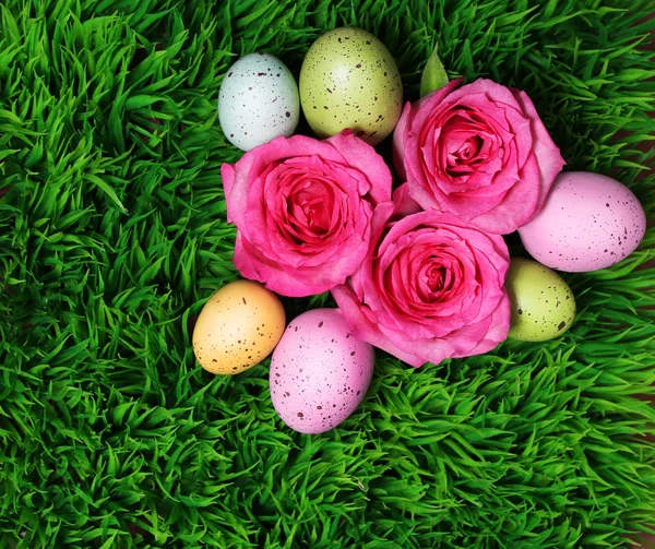 Huevo de Pascua colorido y rosas rosadas sobre hierba verde — Foto de Stock