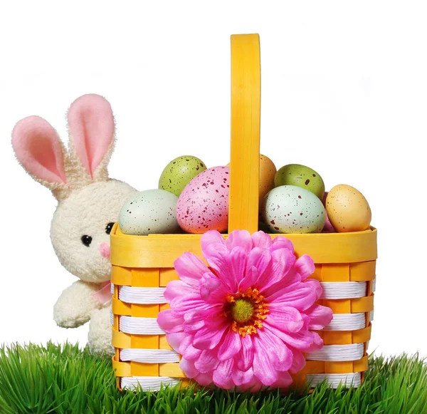 Пасхальная корзина с разноцветными яйцами и кроликом на зеленой траве — стоковое фото