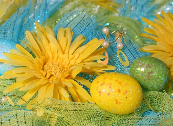 Margaritas amarillas con huevos de Pascua sobre tela brillante . — Foto de Stock