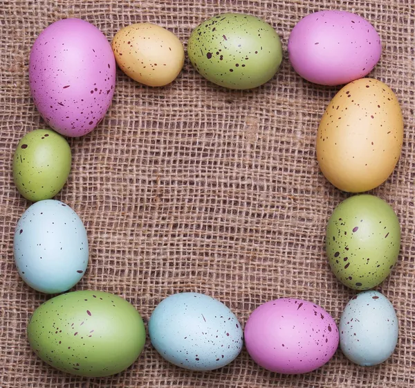 Çuval bezi arka plan üzerinde renkli Paskalya yumurtaları. çerçeve — Stok fotoğraf