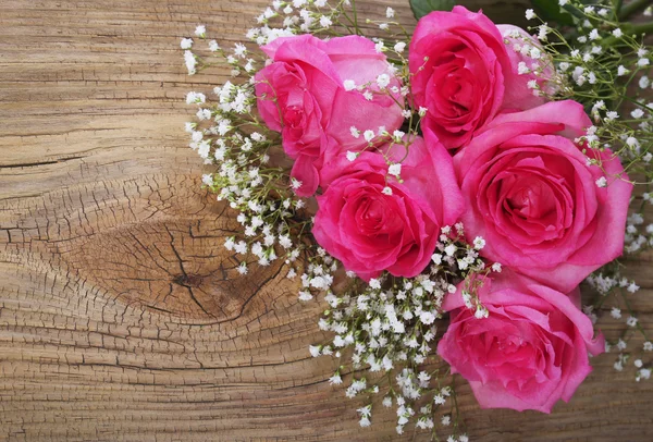 Roze rozen en gypsophila op houten achtergrond — Stockfoto