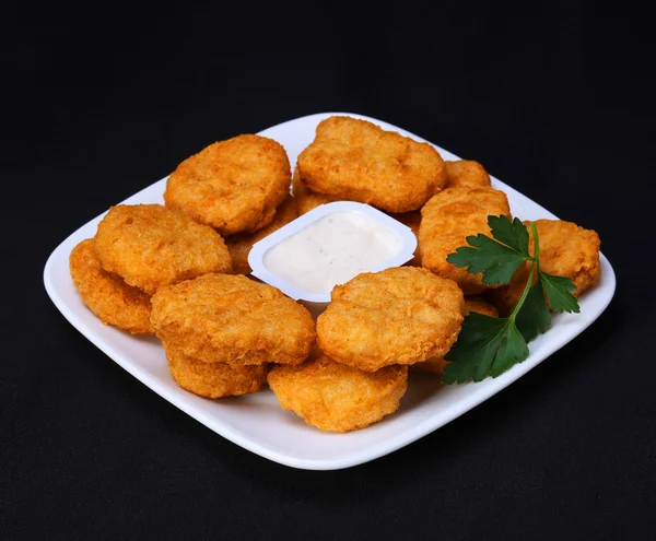 Chicken nuggets on plate with mayo over black background — Stock Photo, Image