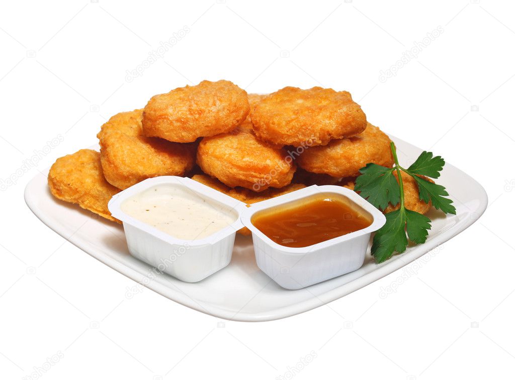 Chicken nuggets in plate with two dressings isolated on white