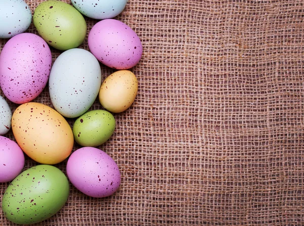 Oeufs de Pâques colorés sur fond de toile de jute — Photo