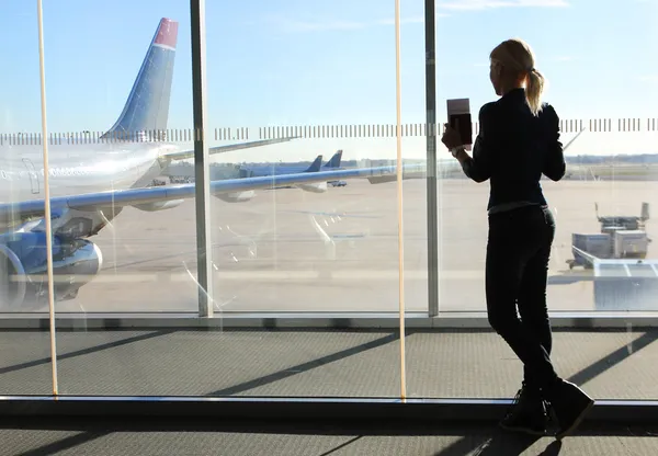 Chica esperando su vuelo en la terminal del aeropuerto. Silueta de Joven —  Fotos de Stock