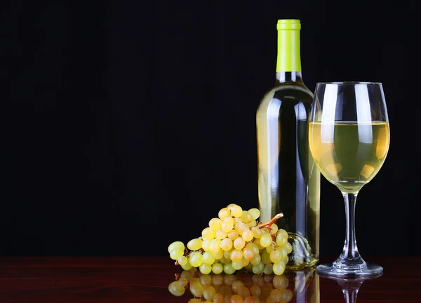 Garrafa de vinho e copo de vinho branco com uvas frescas sobre preto — Fotografia de Stock