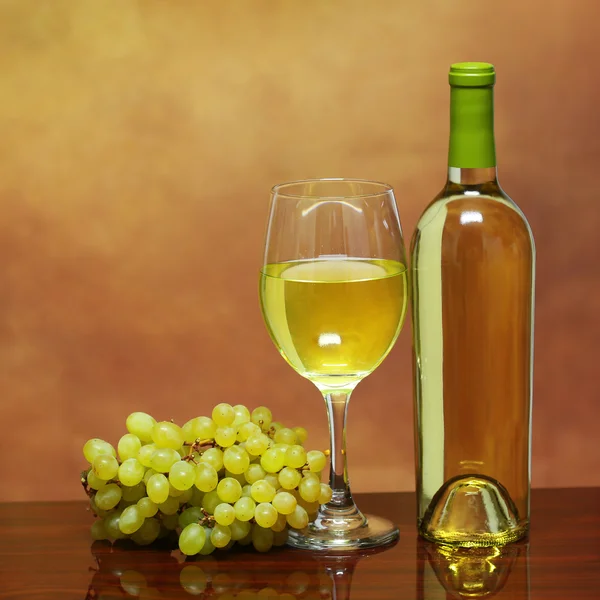 Μπουκάλι κρασί και το ποτήρι λευκό κρασί με νωπά σταφύλια πέρα από το μπεζ — Φωτογραφία Αρχείου