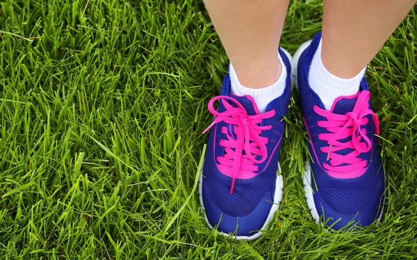 Sport schoeisel op vrouwelijke voeten op groen gras. Closeup uitgevoerd sh — Stockfoto