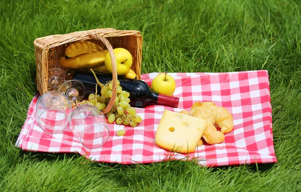 Корзина для пикника с едой на зеленой траве — стоковое фото