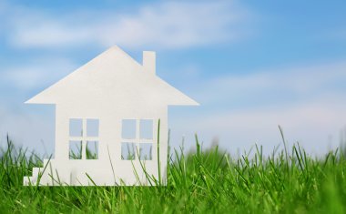 Yeşil çimenlerin üzerinde mavi gökyüzü kağıt ev. mortgage kavramı