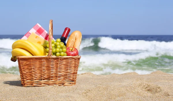 Piknikový koš s jídlem na pláži — Stock fotografie