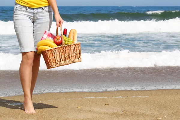 Piquenique na praia. Pernas femininas e cesta com alimentos — Fotografia de Stock