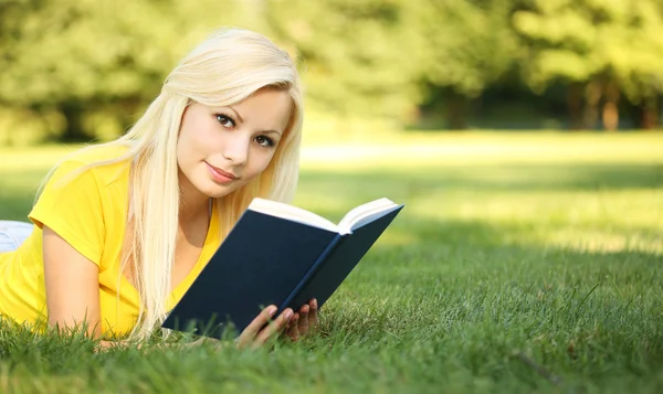 Blondes Mädchen mit Buch auf grünem Gras. schöne Frau im Freien — Stockfoto