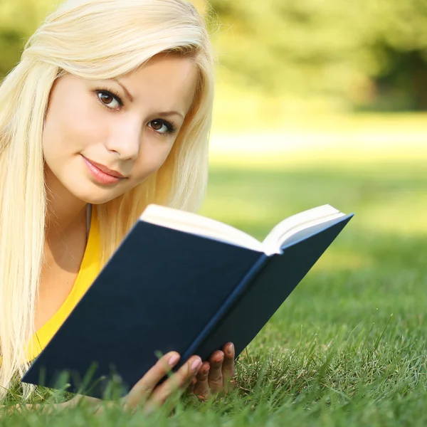 Ragazza bionda con libro sull'erba verde. Bella donna all'aperto — Foto Stock