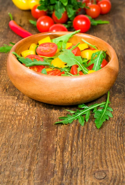 Salad with cherry tomatoes , sweet peppers and arugula in a wooden bowl — Stock Photo, Image