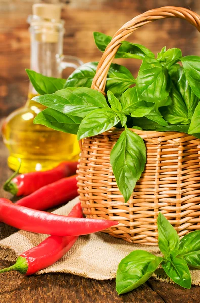 Fresh basil in a basket with chili and vegetable oil — Stock Photo, Image