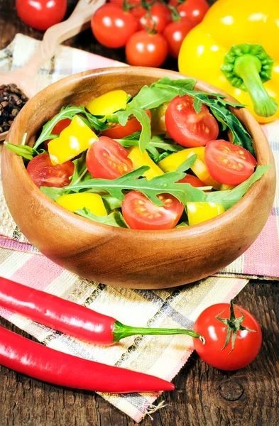 Salad with cherry tomatoes and rugula in a wooden bowl — Stock Photo, Image