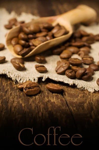 Kaffeebohnen in einer Holzschaufel auf Holzgrund — Stockfoto