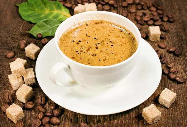 Koffie op een houten achtergrond met bonen en rietsuiker — Stockfoto