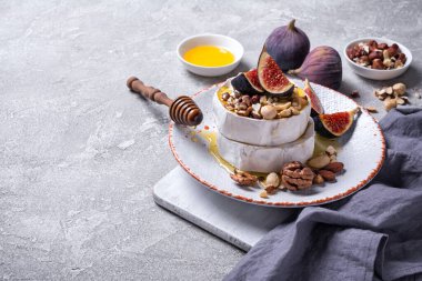 Beyaz peynirli gurme aperatifi ya da gri beton arka planda taze incir, fındık ve bal içeren camembert peyniri.