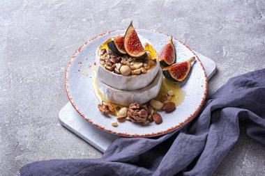 Beyaz peynirli gurme aperatifi ya da gri beton arka planda taze incir, fındık ve bal içeren camembert peyniri.